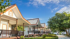 A row of white buildings with brown roofs and wooden balconies, surrounded by greenery and a clear sky. - Scarlet Sails Resort (Koh Rong)