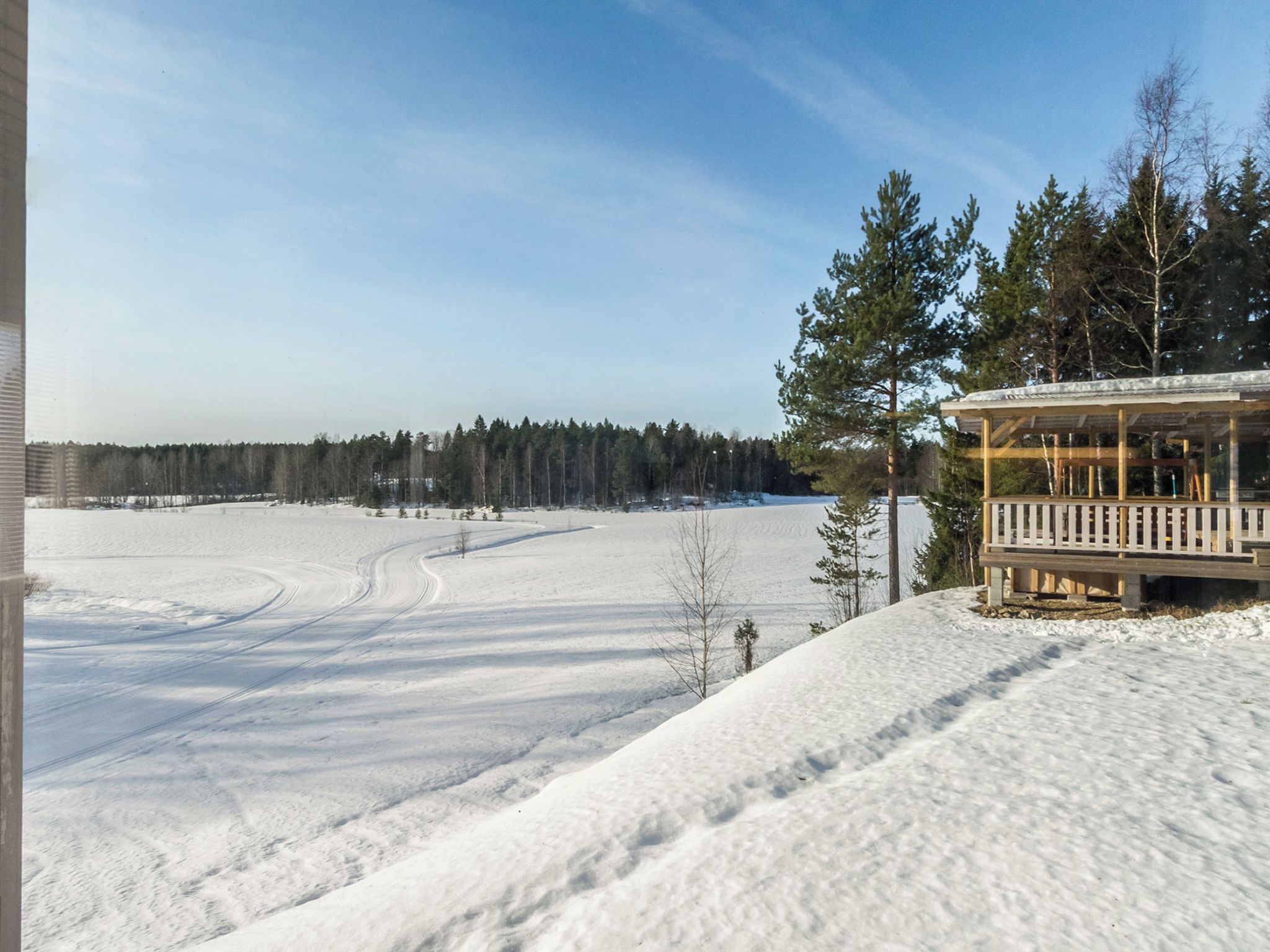 A snow-covered landscape with a wooden building featuring a balcony.