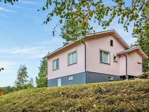 Une maison à deux étages, dotée d’un toit plat, de grandes fenêtres et d’une partie inférieure de couleur grise.
