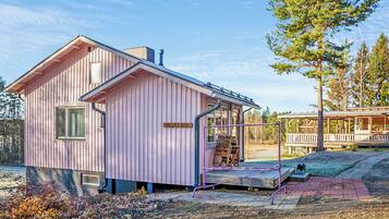 Een roze houten chalet met een veranda en een naambordje met de tekst 'VILLA EBBA'.