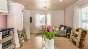 A modern kitchen with white cabinets, a dining table with chairs, and a vase of pink tulips. - Villa ebba by Interhome (Sysmä)
