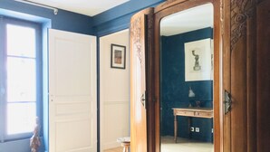 Una habitación con un gran armario de madera, una puerta blanca y un taburete pequeño.