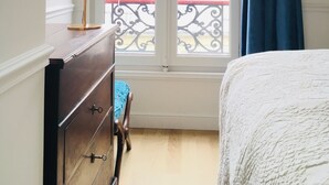 Un dormitorio con cama, cómoda, lámpara y ventana con cortinas.