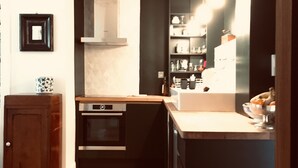 Una cocina compacta con horno integrado, un armario de madera y una encimera.