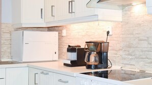 Una cocina moderna con armarios blancos, un refrigerador Bosch, una cafetera y una cocina de inducción.