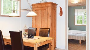 Una mesa de comedor de madera con sillas, un mueble de madera y una cama en la habitación contigua.