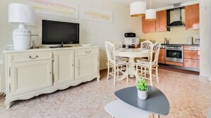 Un espace de vie compact comprenant un coin repas, une kitchenette et un téléviseur posé sur un meuble.