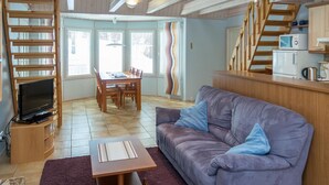 A cozy living room with a sofa, a coffee table, a TV, and a dining area with a table and chairs. - Nelikko a by Interhome (Kuusamo)