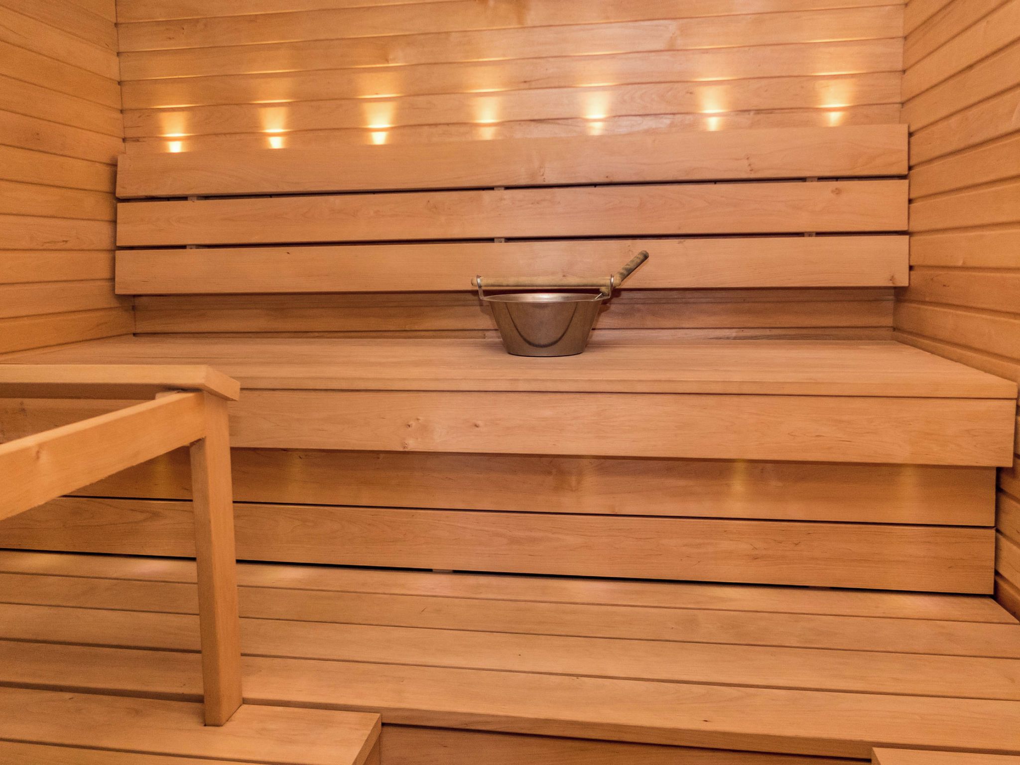 Un sauna avec des bancs en bois et un seau en métal.
