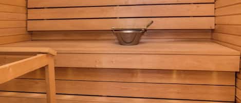 Una sauna con panche in legno e un secchio di metallo.