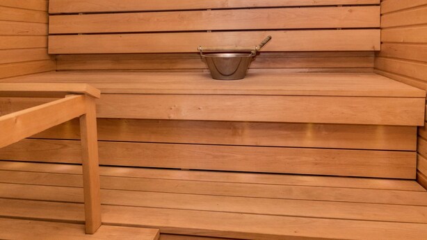 A sauna with wooden benches and a metal bucket. - Nelikko a by Interhome (Kuusamo)