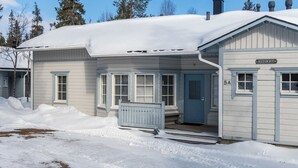 A two-story building with a snow-covered roof and a blue door. - Nelikko a by Interhome (Kuusamo)
