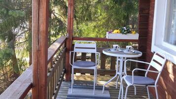 A wooden deck with a table and two chairs, a window, and a railing.