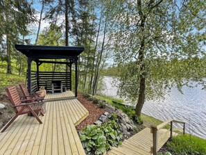 A wooden deck with a gazebo, seating area, and a view of a lake. - Hellinki by Interhome (Virrat)