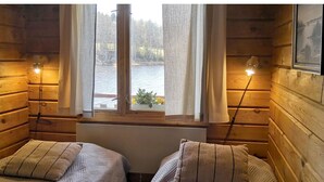A cabin room with two beds, a window with curtains, a nightstand, and a lamp. - Hellinki by Interhome (Virrat)