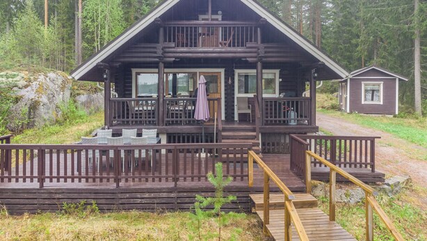 Eine Hütte mit Veranda, einer kleinen Terrasse und einer Treppe zum Eingang.