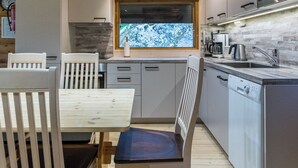Eine moderne Küche mit integriertem Mikrowellenherd, einer Kaffeemaschine und einem Fenster mit Blick auf Bäume.