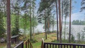 Eine Holzterrasse führt zu einem See, der von hohen Bäumen umgeben ist.