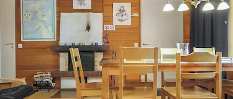 Un intérieur en bois comprenant une table à manger, des chaises, une carte et une horloge au mur.