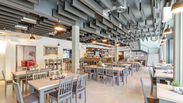 A modern restaurant with multiple dining tables and chairs, a bar area, and a staircase leading to an upper level. - Amazing home in Thale with sauna (Thale)