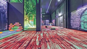A hallway with a red wooden floor, green walls, and a tree mural. There are doors and a small table with a chair. - Amazing home in Thale with sauna (Thale)