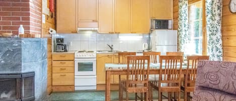 A compact kitchen with wooden cabinets, a stove, a microwave, and a refrigerator.