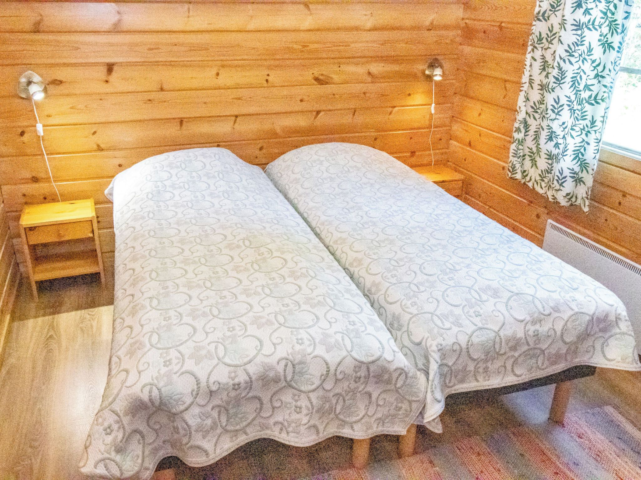 Un letto matrimoniale con copripiumino decorato in una stanza in legno con due lampade ai comodini.