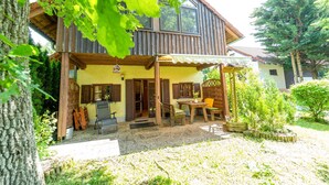 Een houten huis met twee verdiepingen, een overdekt terras, een houten terras en een kleine tuin.