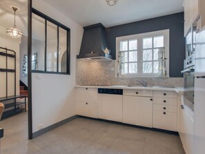 A modern kitchen with white cabinets, a tiled backsplash, and a window above the sink. - Portivy Moulin by Interhome (Quiberon)