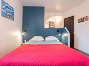 A bedroom with a bed, two bedside lamps, a blue accent wall, and a painting on the wall. - Portivy Moulin by Interhome (Quiberon)