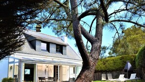 A two-story house with a large tree in the front yard.