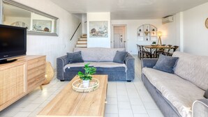 Una sala de estar moderna con un sofá, una mesa de centro, un televisor y una escalera que conduce a otra habitación.