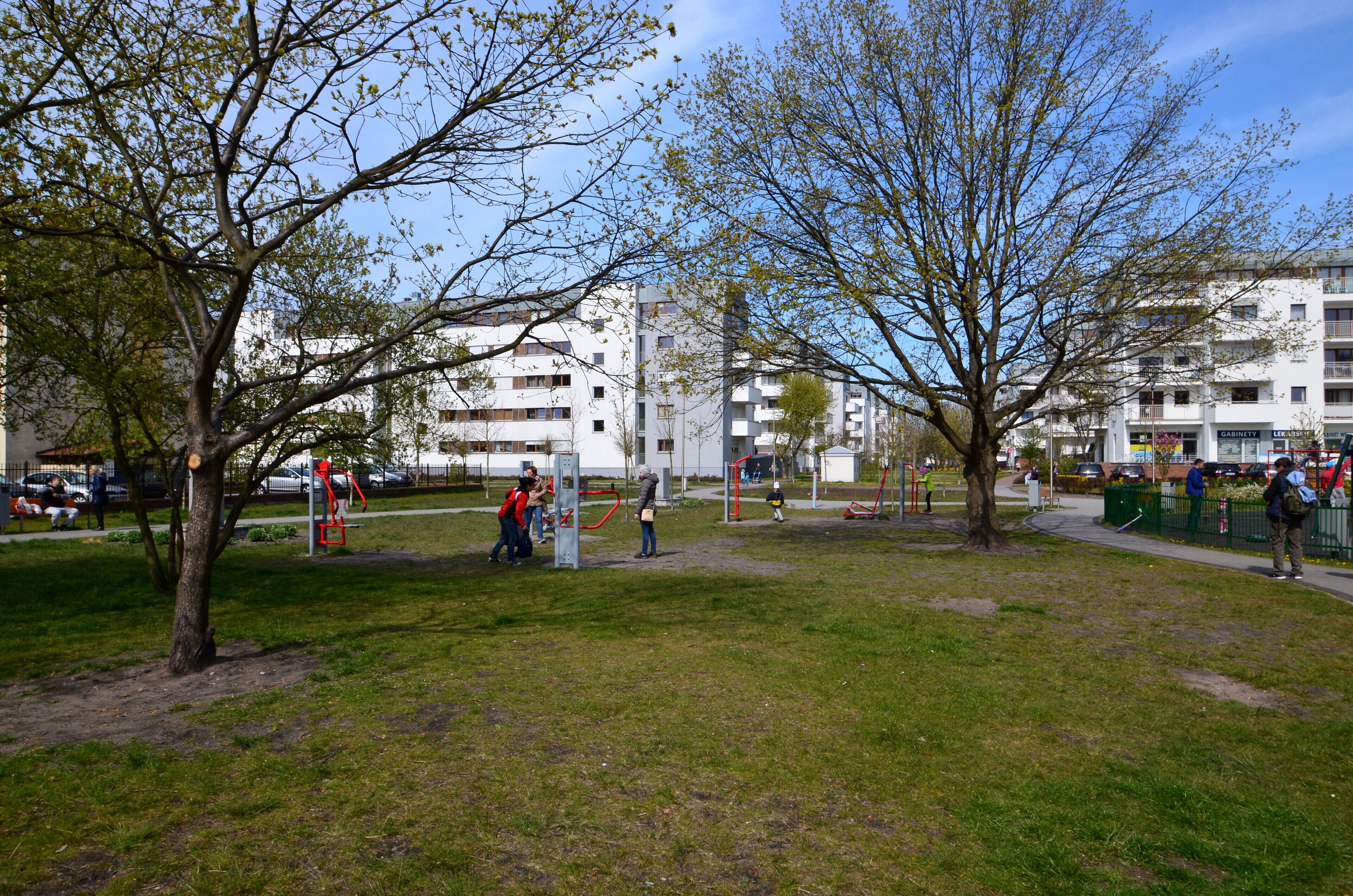Ein Park mit Spielgeräten, Bäumen und einem Gebäude im Hintergrund.