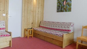 A wooden room with a sofa, a small table, and a chair. - 10m from ski slopes, 1st floor, balcony, 27m², Méribel-Mottaret (Méribel - Les Allues)