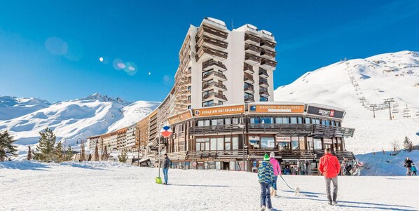 A ski resort building with multiple balconies and signage for 'Ecole du Ski Francais' and 'Banque Populaire'.