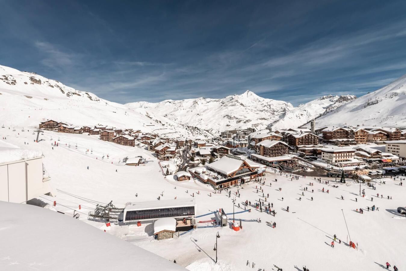 Ein verschneiter Bergort mit Skipisten, Gebäuden und einer Seilbahn.