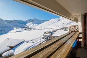Une vue depuis un balcon donnant sur une vallée enneigée, avec des montagnes en arrière-plan.