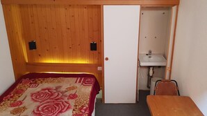 A small room with a bed, a wooden wardrobe, a small table, and a bathroom with a sink. - 50m from resort center, 8th floor, view mountain, balcony, tv, 42m², Les Arcs (Les Arcs)