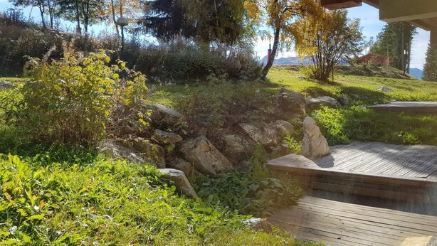 A wooden deck leading to a stone wall with a view of a grassy hillside and trees. - 50m from resort center, 8th floor, view mountain, balcony, tv, 42m², Les Arcs (Les Arcs)