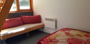 A room with a bed, a window, a radiator, and a wooden bench with cushions. - 50m from resort center, 8th floor, view mountain, balcony, tv, 42m², Les Arcs (Les Arcs)