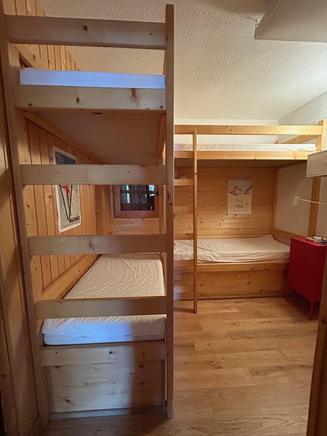 A bunk bed room with wooden walls and a red table.
