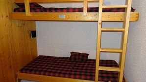 Una cama individual superpuesta con escalera de madera y ropa de cama a cuadros.