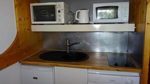 Una kitchenette compacta con un lavamanos, dos microondas y una cafetera.