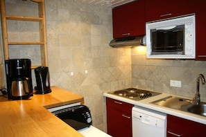 A compact kitchen with a microwave, stove, coffee maker, and dishwasher.