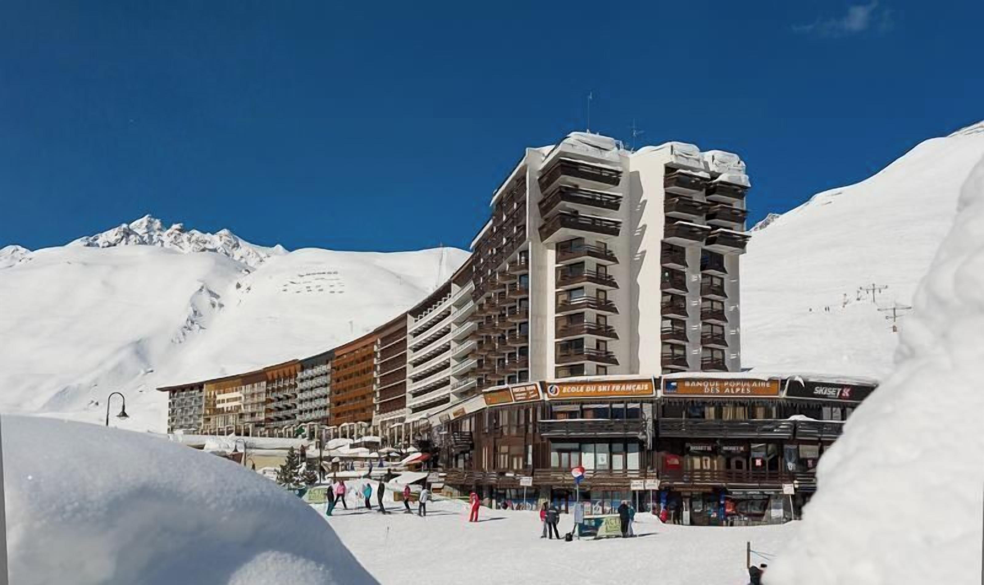 A multi-story hotel with balconies, located in a snowy mountainous area.