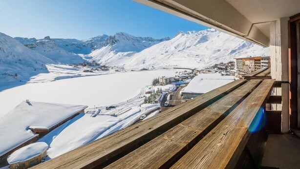 Uitzicht vanaf een balkon over een met sneeuw bedekte vallei, met bergen op de achtergrond.