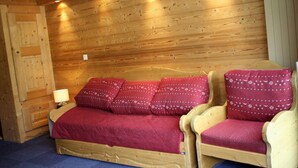 Een houten kamer met een bed, twee stoelen, een nachtkastje en een lamp.