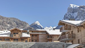 A wooden chalet with a balcony, set against a backdrop of snow-covered mountains and clear skies. - Wifi, 200m from shops, fitness, swimming pool, sauna, hammam, balcony, tv, ski locker, 60m², Samoëns (Samoëns)