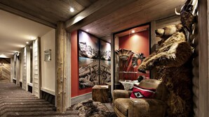 A hallway with a wooden floor, a leather armchair with a red pillow, and a wall displaying animal skulls and fur. - Wifi, 200m from shops, fitness, swimming pool, sauna, hammam, balcony, tv, ski locker, 60m², Samoëns (Samoëns)