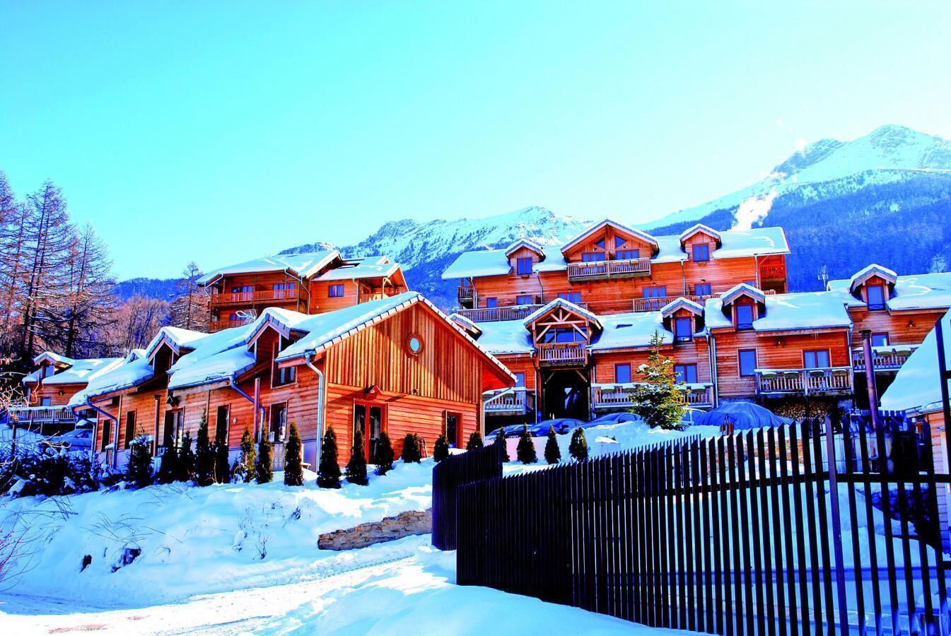 Un chalet en bois doté de plusieurs balcons, avec une montagne enneigée en toile de fond.